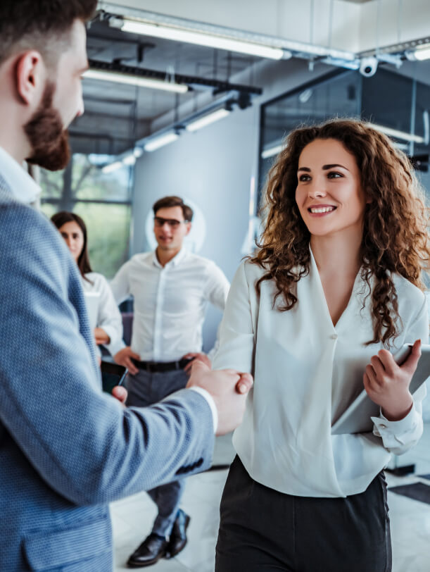 happy business woman smiling and shaking a client's hand in office